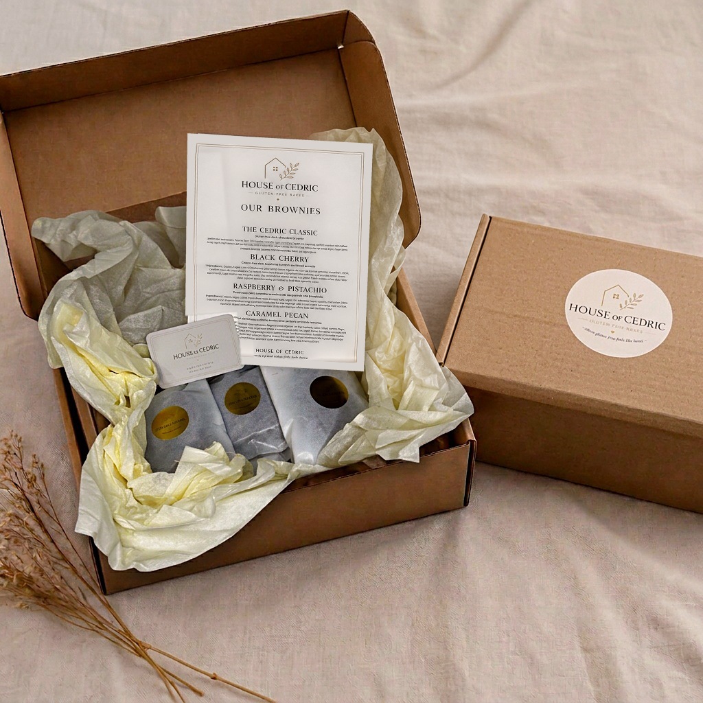 Open kraft delivery box with tissue, wrapped brownies and printed cards beside the matching closed box